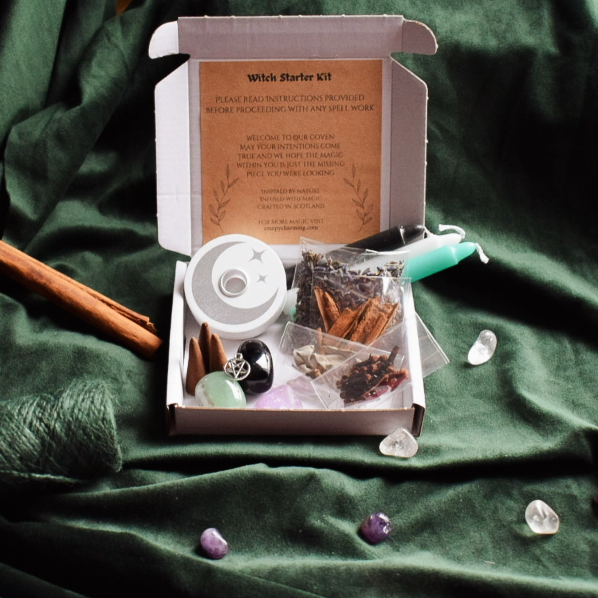 Witch starter kit with spellbook and crystals on a green fabric background