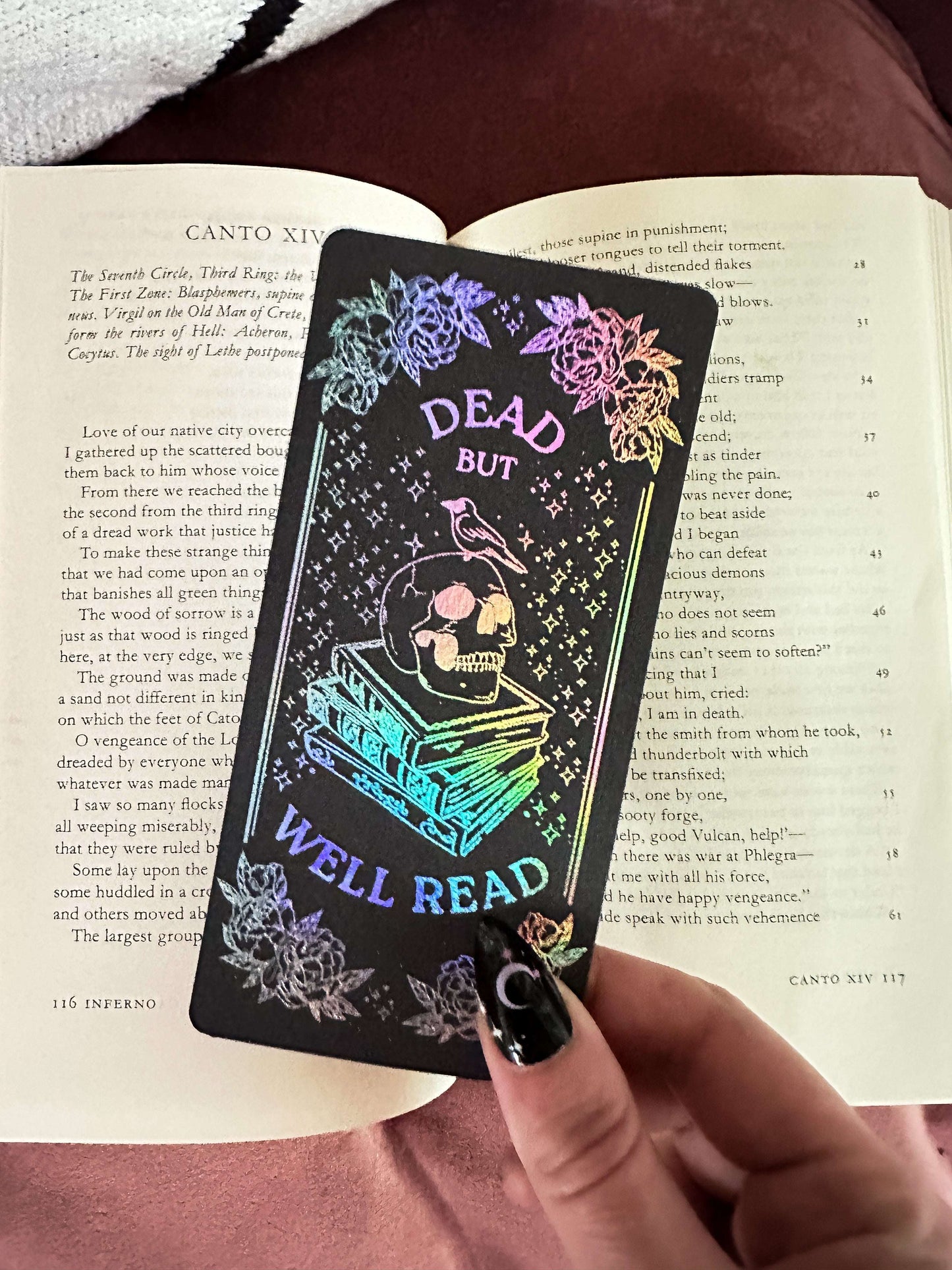 Black bookmark with colorful text and design held over an open book