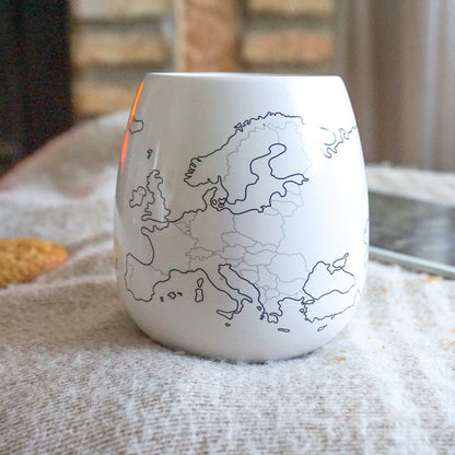 White ceramic tumbler with a black outline map of Europe on a textured surface.