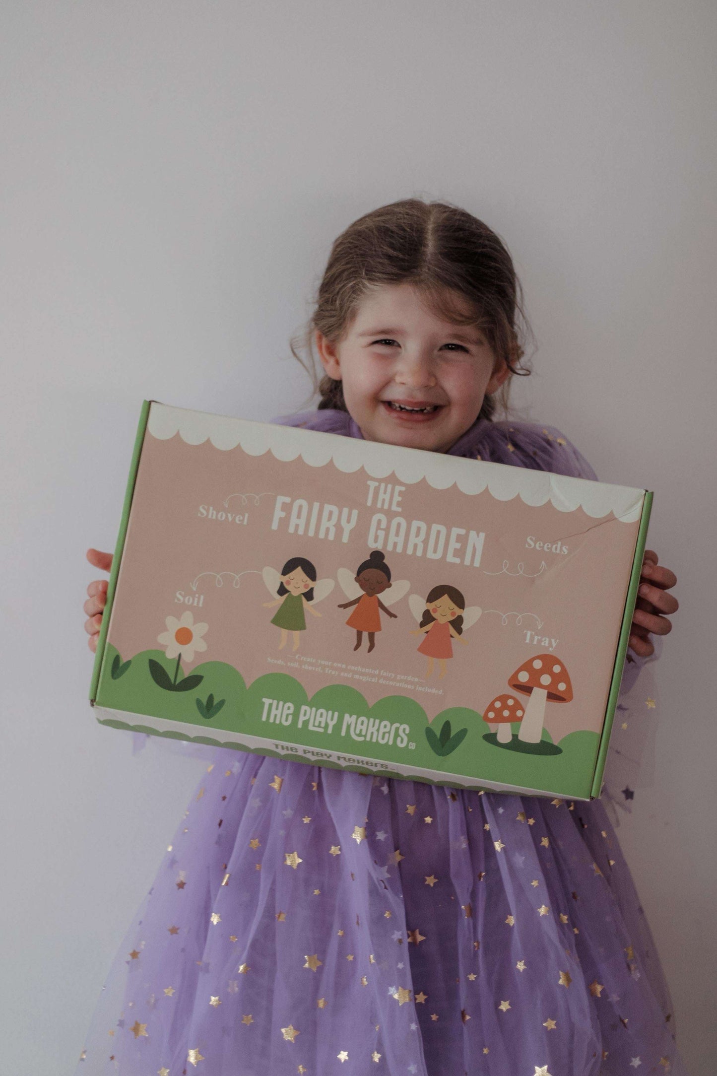 Child holding a fairy garden kit box with a plain background
