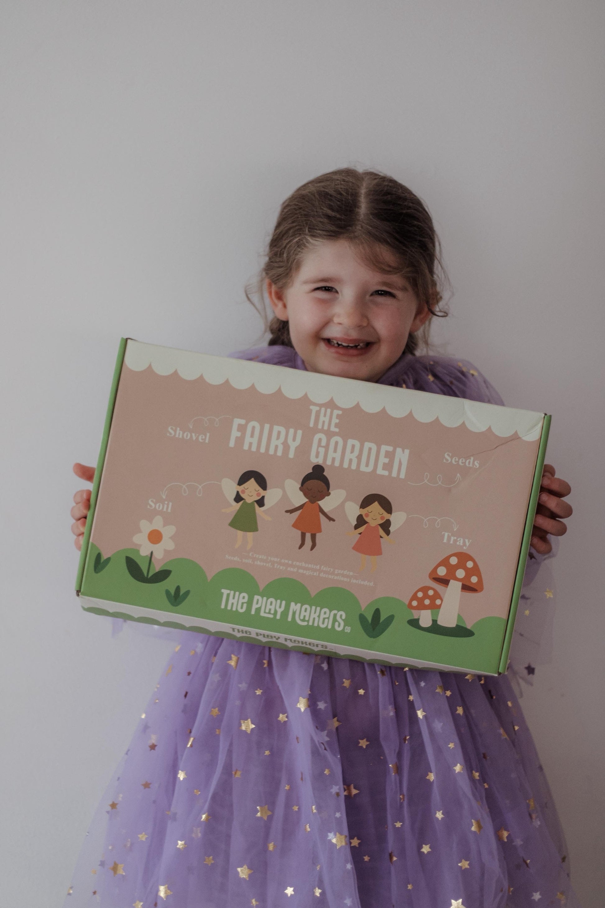 Child holding a fairy garden kit box with a plain background