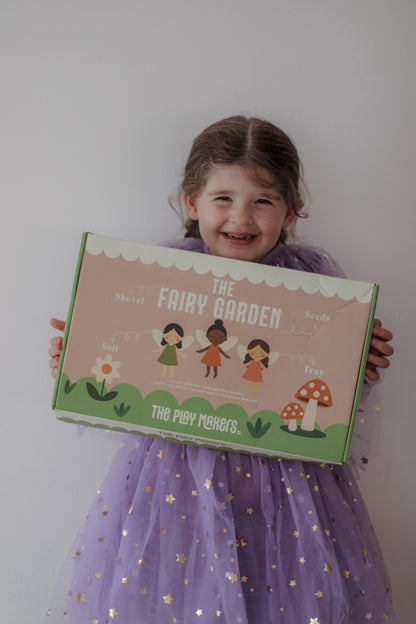 Child holding a fairy garden kit box with a plain background