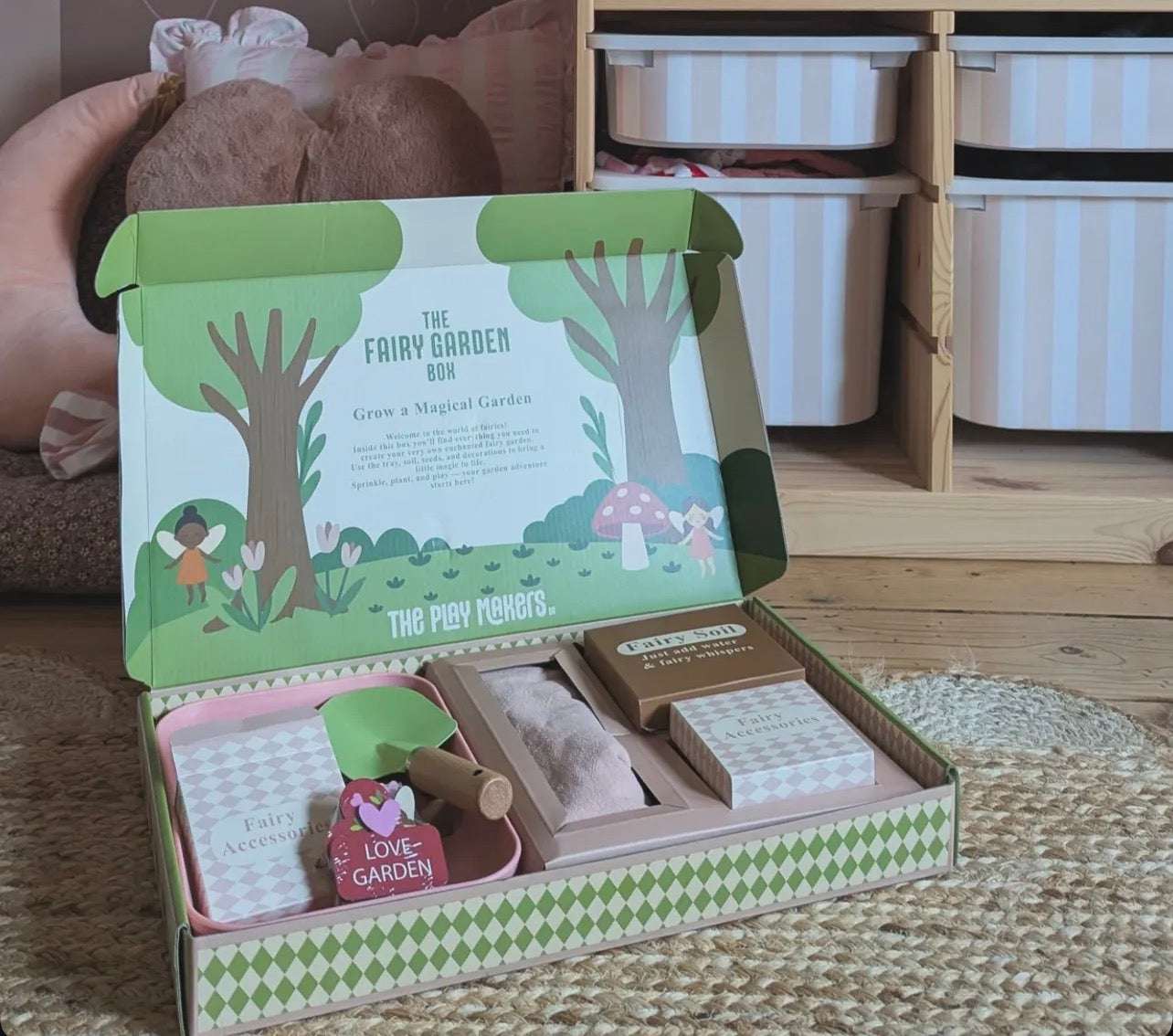 Fairy garden kit with instructions and small plants in a box on a wooden floor.