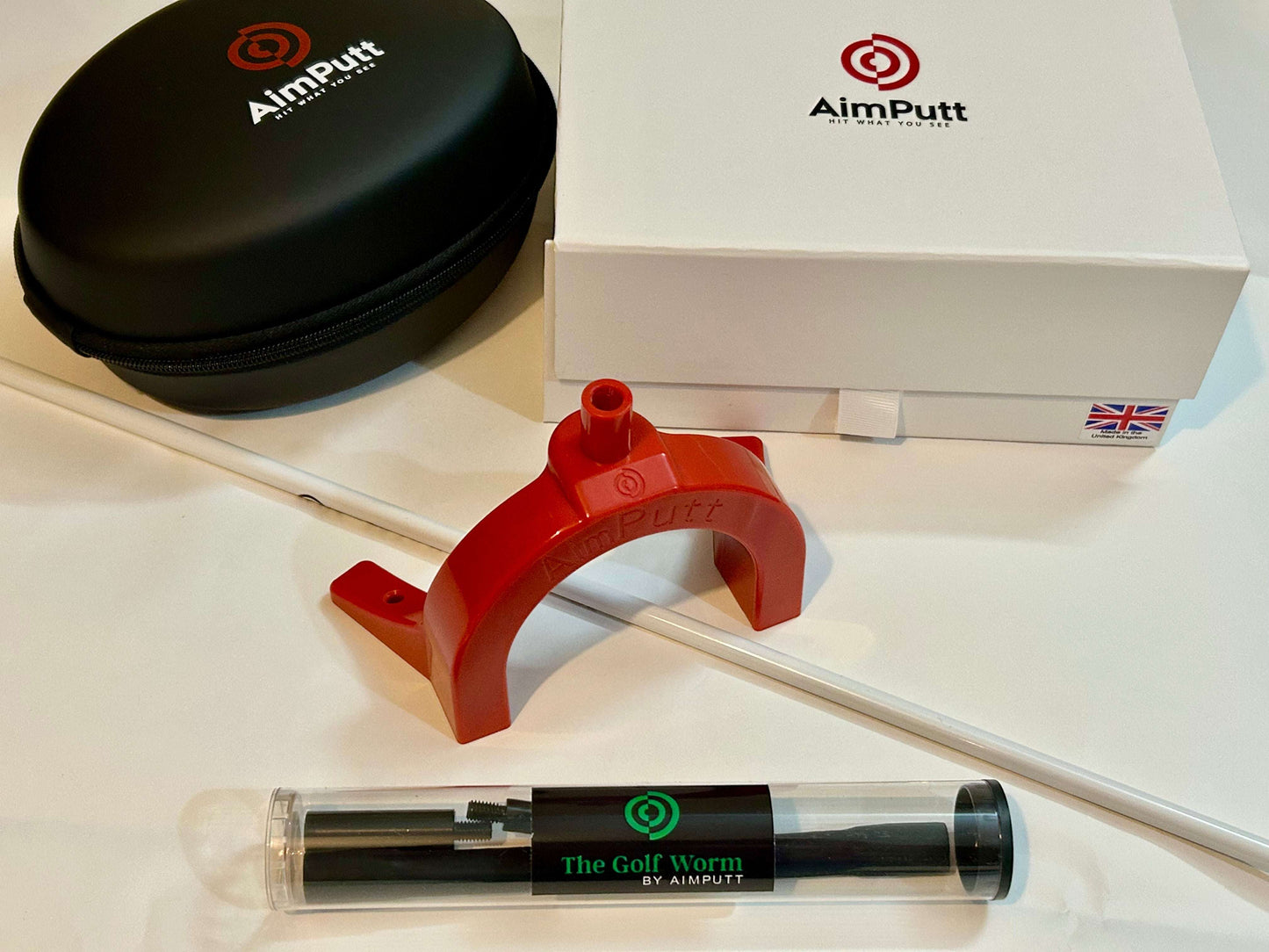 AimPutt golf training aid set with red device, black case, and tube on a white surface.