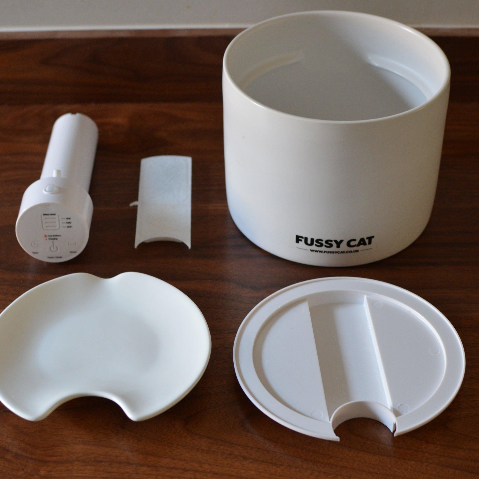 White pet product set with 'Fussy Cat' branding on a wooden surface
