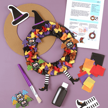 Halloween wreath craft kit with colorful paper, paint, and instructions on a purple background