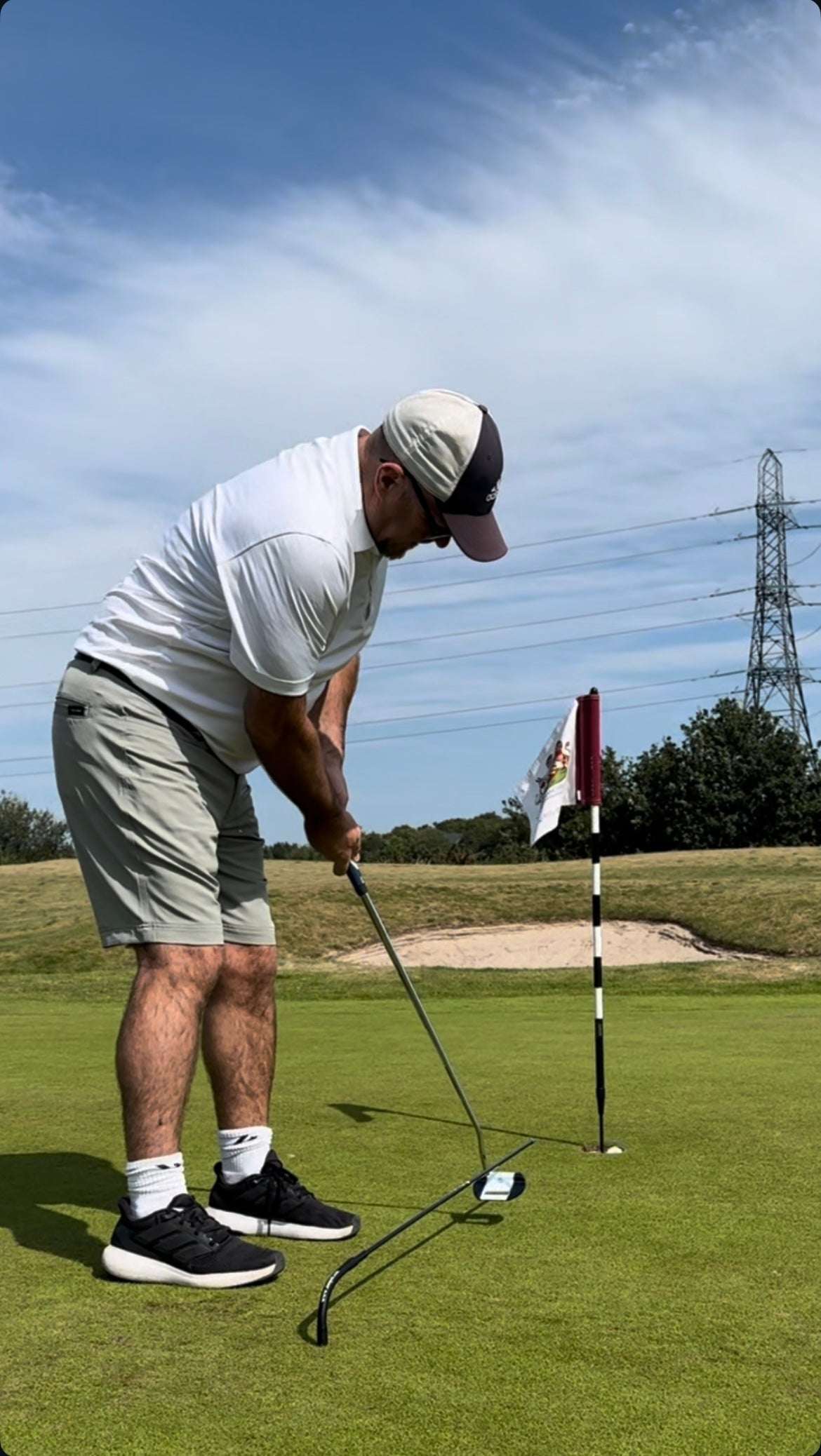 Man playing golf on a green course with a clear sky