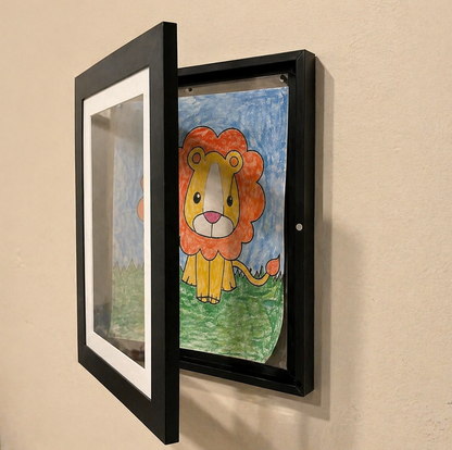 Children's drawing of a lion in a black frame on a beige wall.