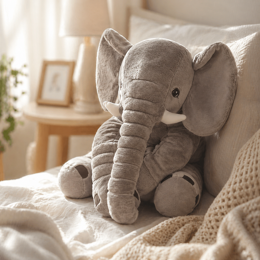Elephant plush toy sitting on a bed 