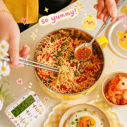 Hot bowl of noodles with a spoon and chopsticks, surrounded by various dishes and a timer on a light background.