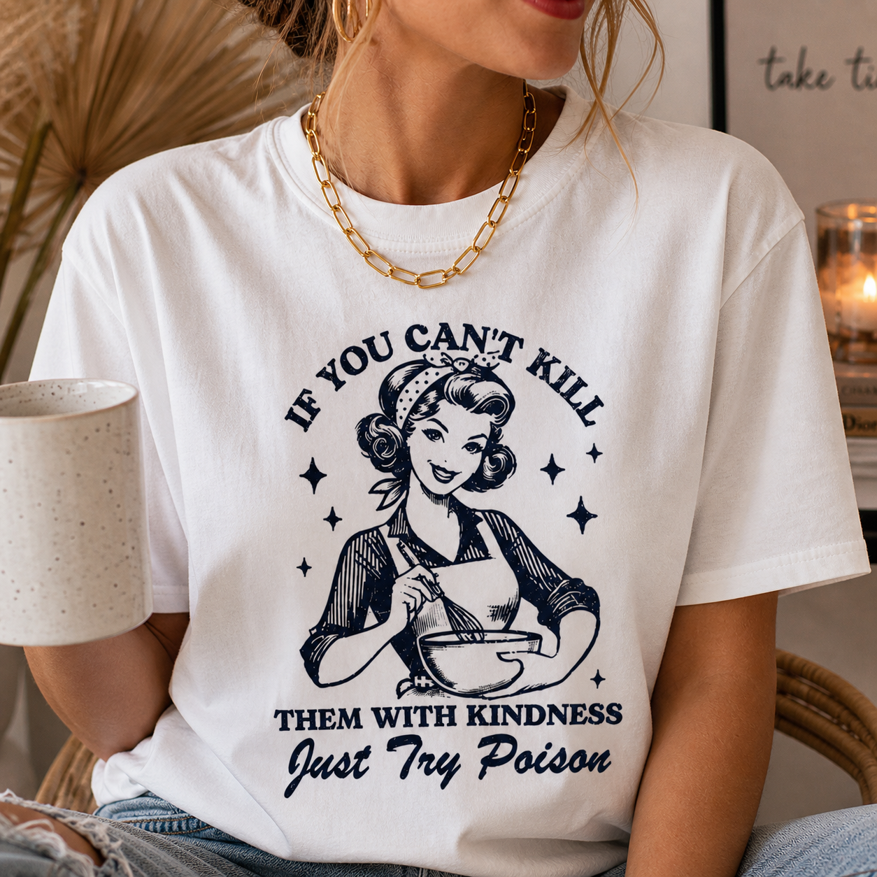 Person wearing a white t-shirt with a graphic and text, sitting indoors.