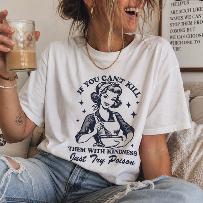 Person wearing a white t-shirt with a graphic and text, holding a glass of coffee.