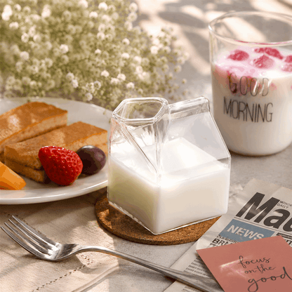 Glass milk bottle with a glass of milk, toast, and berries on a table with 'Good Morning' coffee.