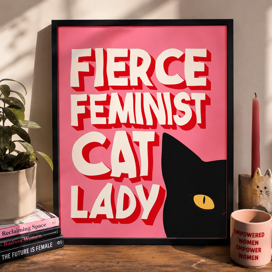 Framed poster with 'Fierce Feminist Cat Lady' text on a pink background, displayed on a shelf with decor items.