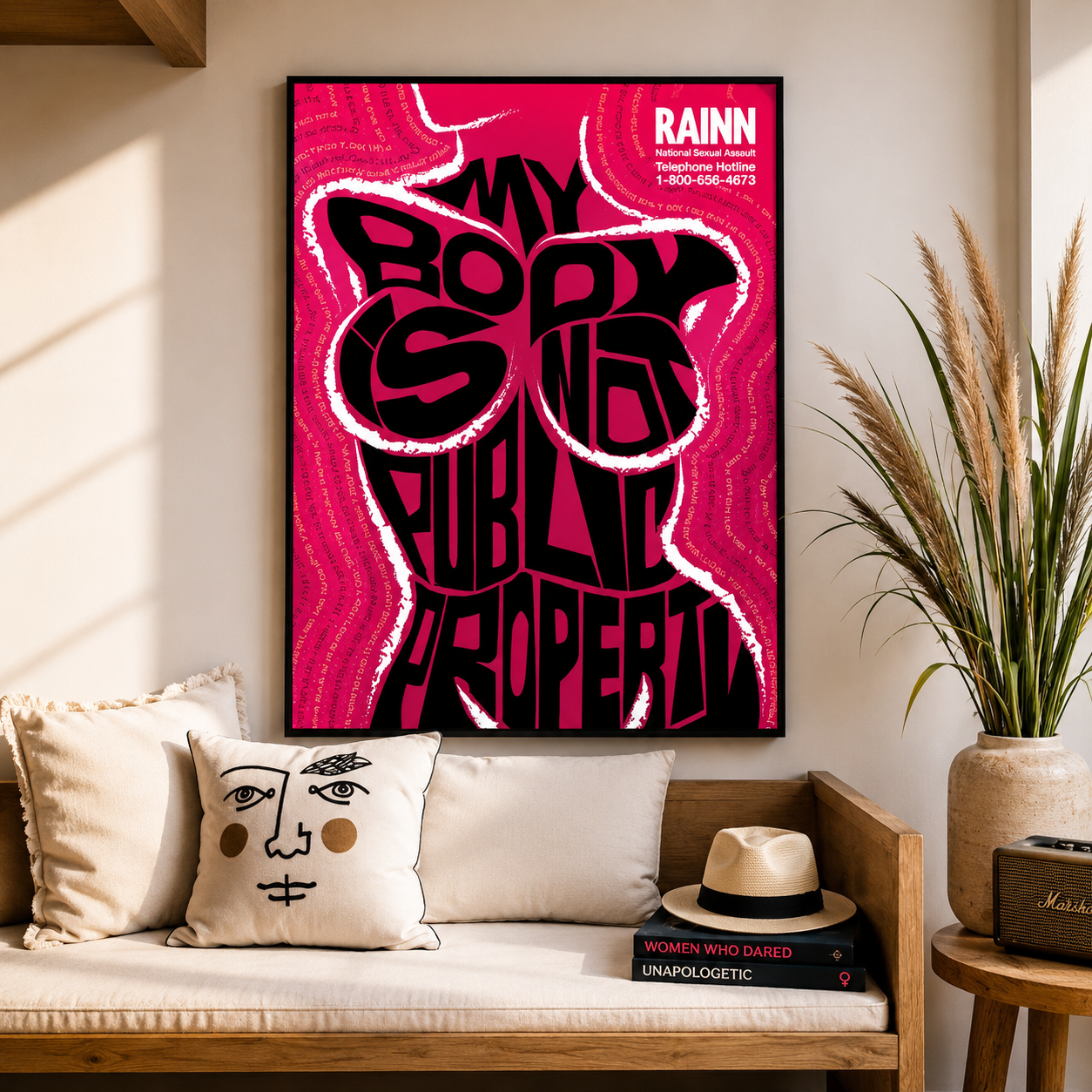 Framed poster with bold text on a wall above a couch with decorative pillows and books.