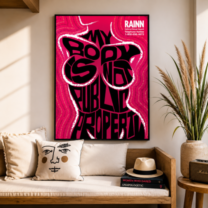 Framed poster with bold text on a wall above a couch with decorative pillows and books.