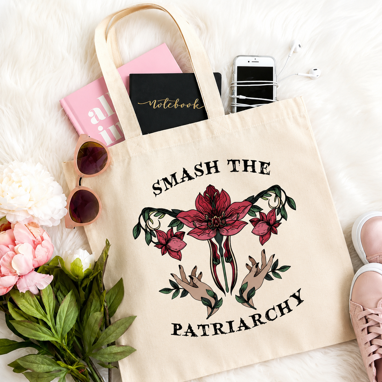 Tote bag with 'Smash the Patriarchy' design on a white surface with accessories.