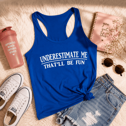 Blue tank top with 'Underestimate Me That'll Be Fun' text, sneakers, notebook, and sunglasses on a textured surface.