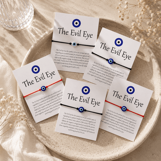 Multiple 'The Evil Eye' bracelets on cards with text on a beige plate.