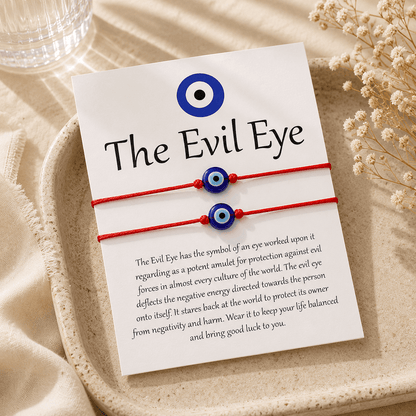 Two red bracelets with blue evil eye symbols on a card with text about the evil eye.