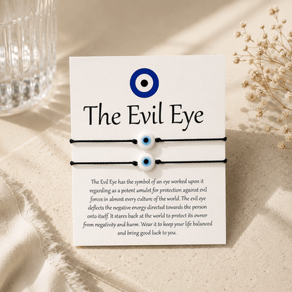 Evil eye bracelet set with card explaining the symbol on a beige surface.