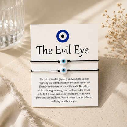 Evil eye bracelet set with card explaining the symbol on a beige surface.