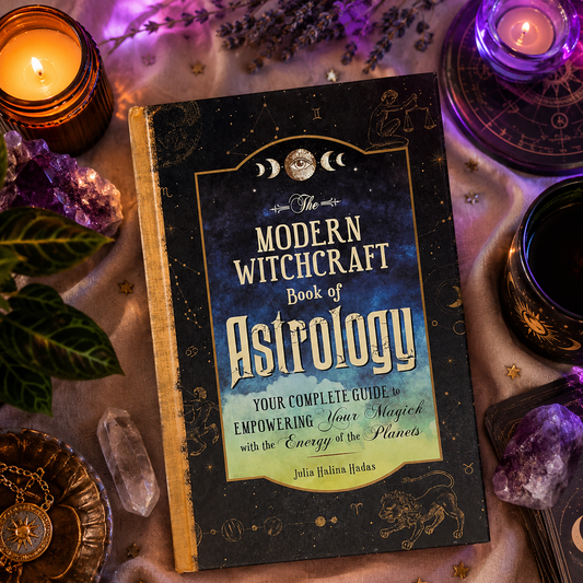 Book titled 'The Modern Witchcraft Book of Astrology' surrounded by candles, crystals, and other mystical items.