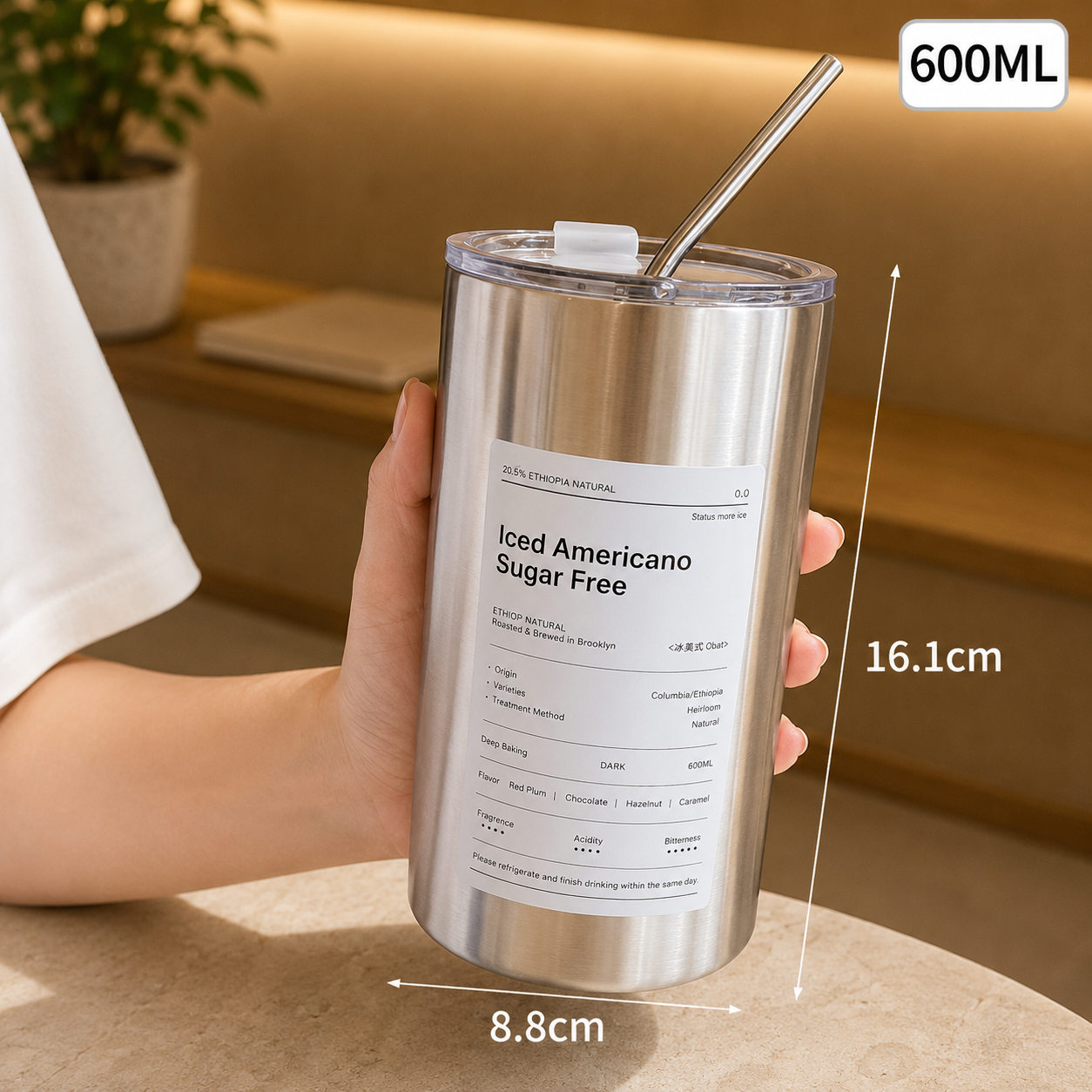 Stainless steel tumbler with a straw held by a hand, labeled '600ML' and 'Iced Americano Sugar Free'.