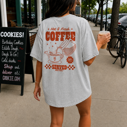 Person wearing a t-shirt with a coffee-themed design on a sidewalk.