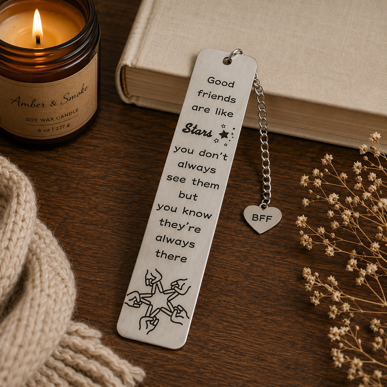Bookmark with motivational quote next to a candle and book on a wooden surface