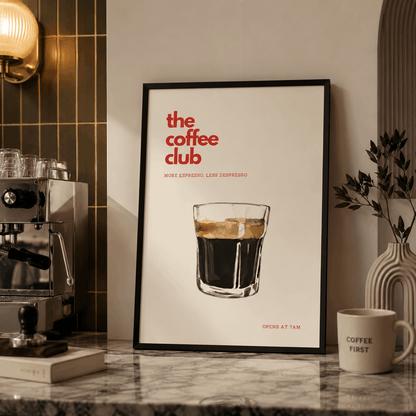 Framed poster of 'the coffee club' with a glass of coffee on a countertop with coffee-making equipment.