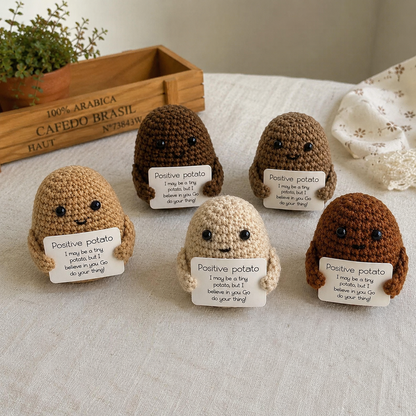 Five crochet potato characters with 'positive potato' signs on a light surface.