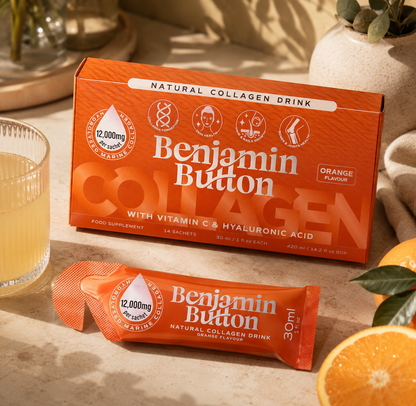Benjamin Button Collagen drink packaging on a table with an orange and a glass of liquid.