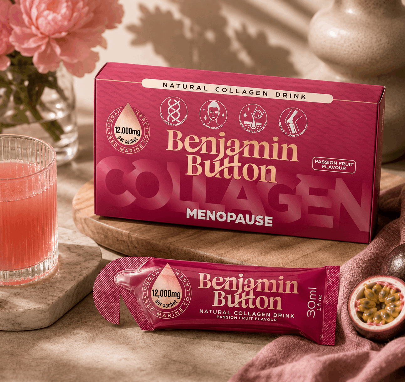 Benjamin Button collagen drink packaging with a glass of pink juice and flowers in the background.