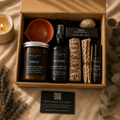 Box of Kati Kaia products including candles, oils, and a crystal on a beige background.