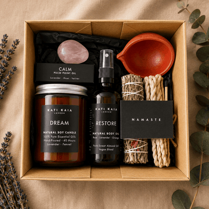Gift set with candles, oils, and other items in a box on a wooden surface.