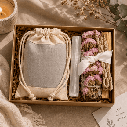 Gift set with a drawstring bag, crystal, and dried flowers in a box on a soft surface.