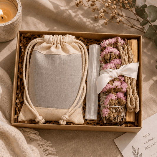 Gift set with a drawstring bag, crystal, and dried flowers in a box on a soft surface.