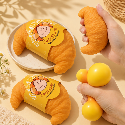 Two plush croissant toys with a hand holding one, on a beige background.