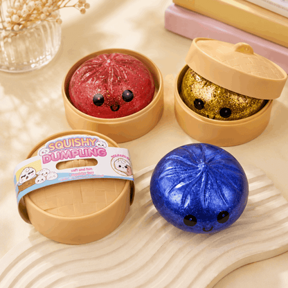Three colorful squishy dumplings with a steamer on a light wooden surface.