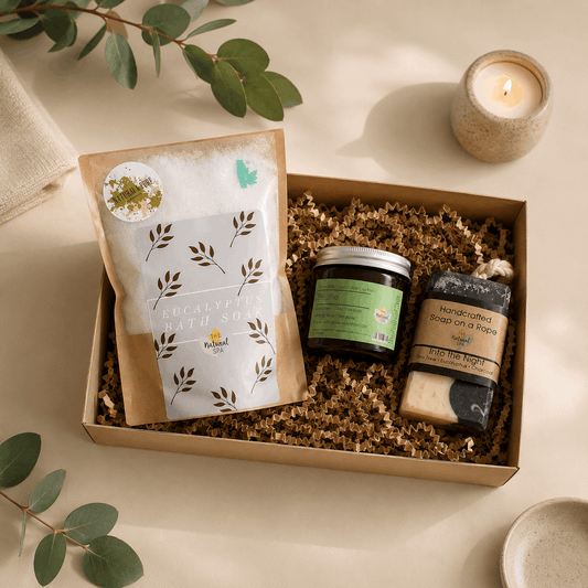 Gift box with natural products including soap, candle, and packaging on a light background