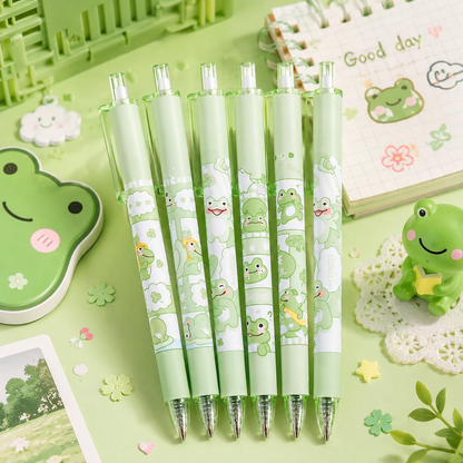 Set of green pens with frog designs on a green background with stationery items.