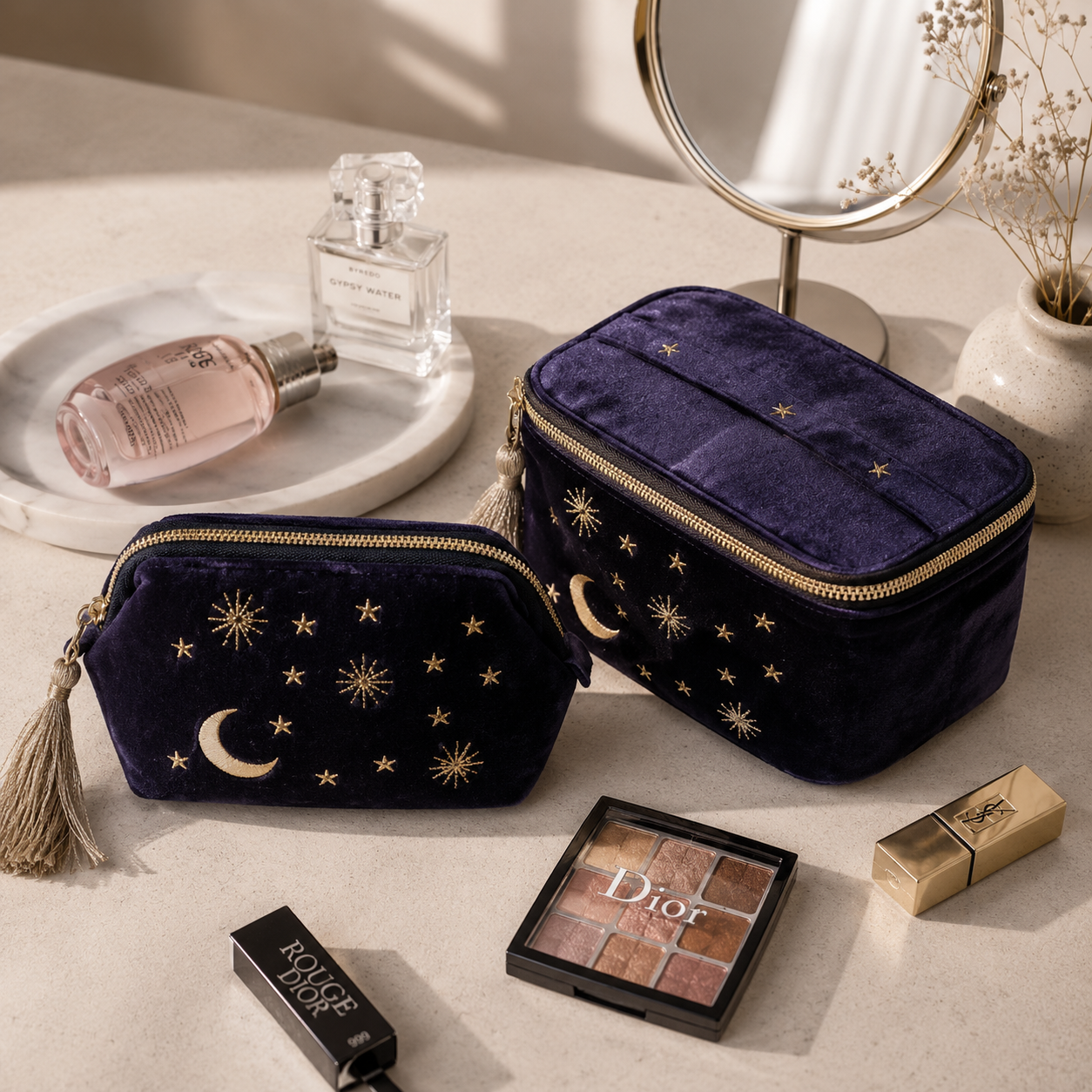 Navy blue makeup bags with celestial designs on a surface with cosmetic items.