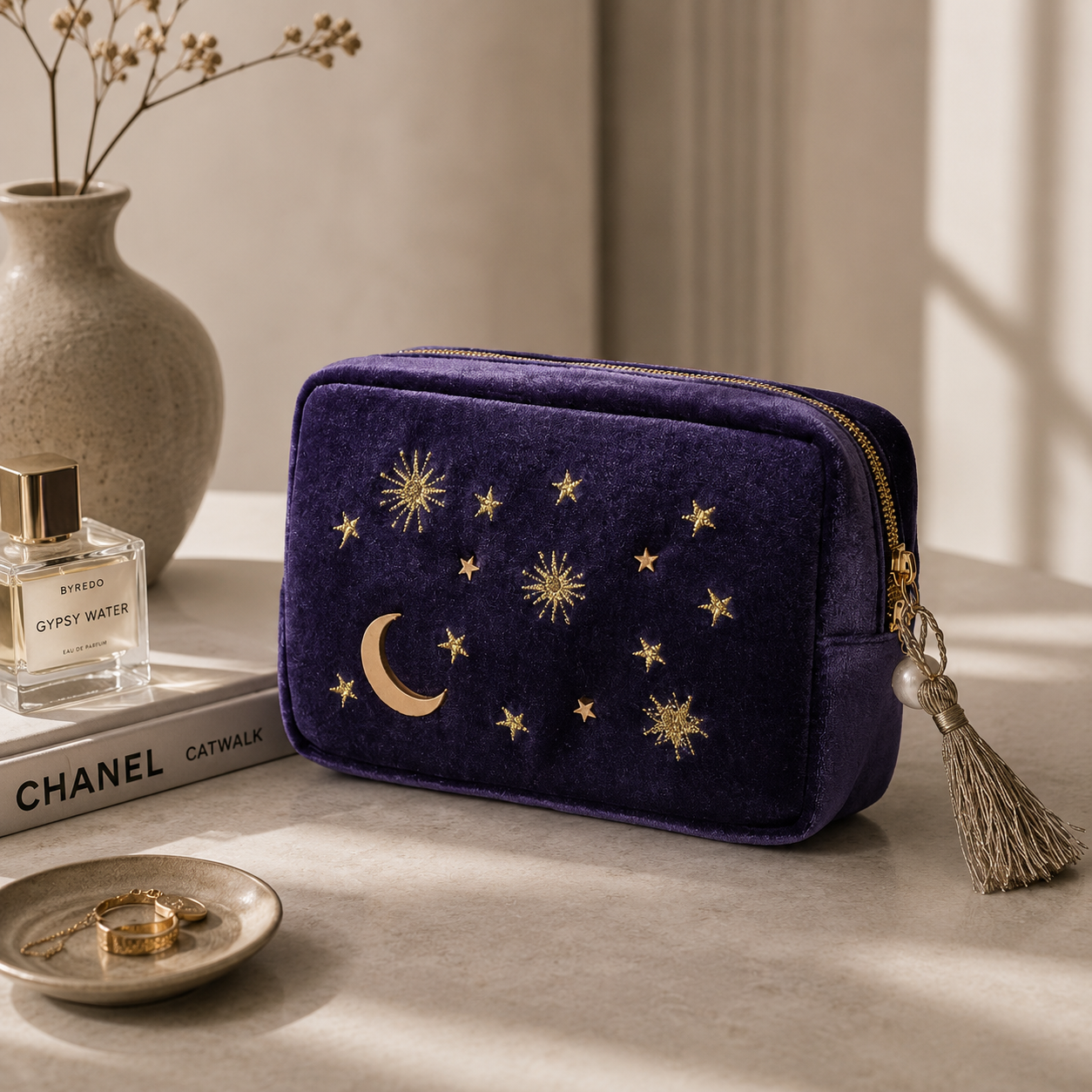 Navy blue pouch with star and moon designs on a surface with books and a vase in the background