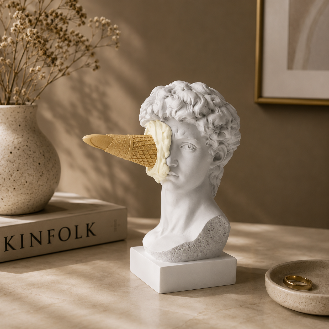 Statue head with ice cream cone on a table next to a 'KINFOLK' book