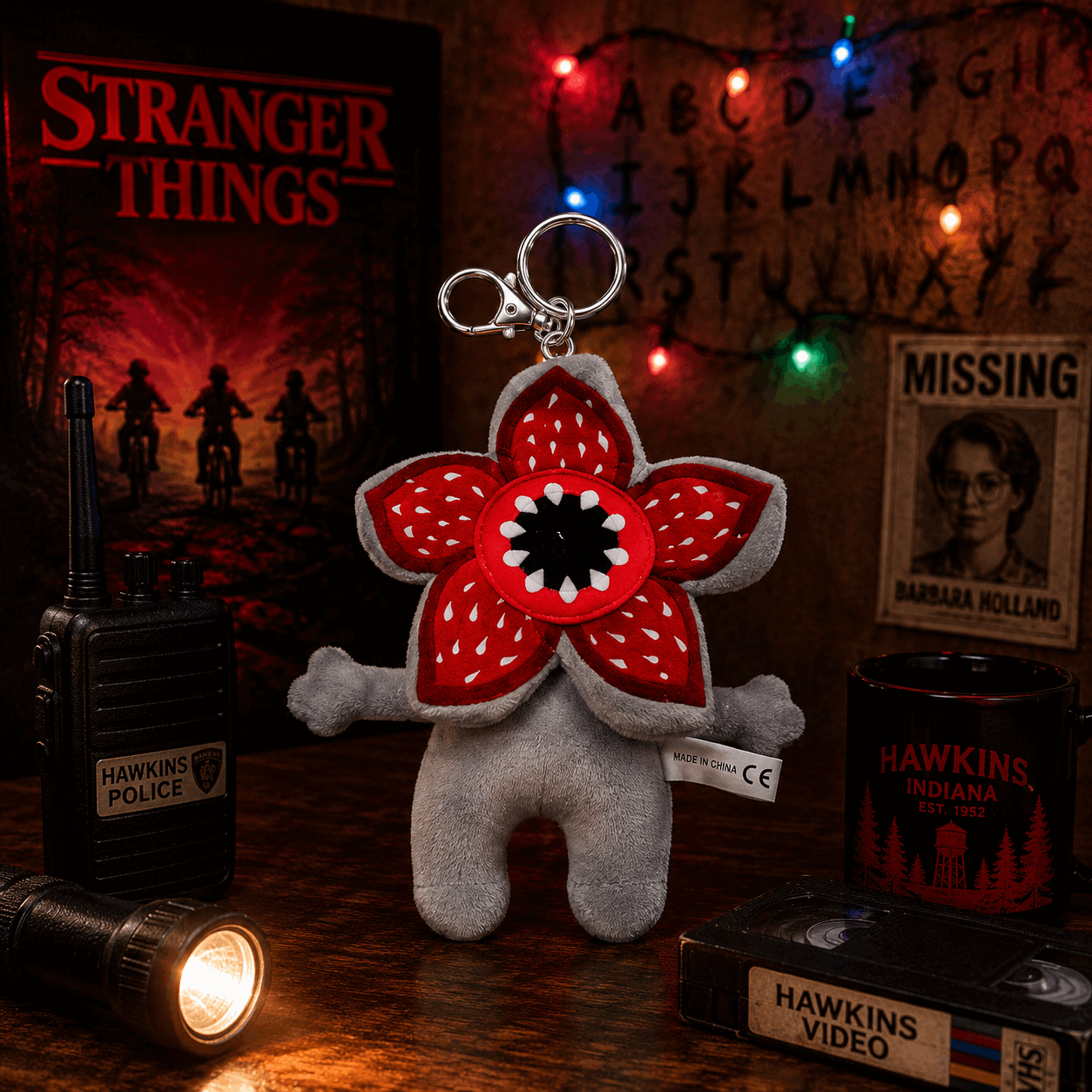 Stranger Things-themed keychain with red flower design on a wooden surface with props.