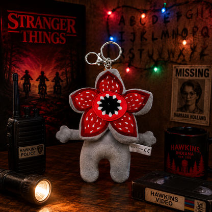 Stranger Things-themed keychain with red flower design on a wooden surface with props.