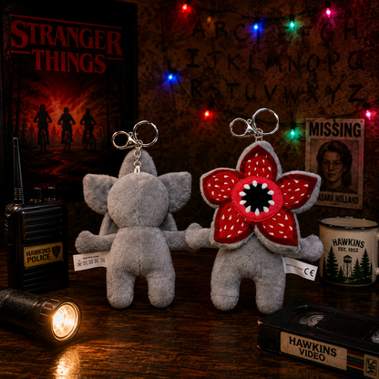 Two plush keychains resembling characters from 'Stranger Things' on a table with decorative items.