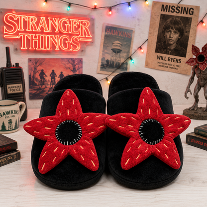 Black slippers with red star design on a surface with 'Stranger Things' themed decor in the background.