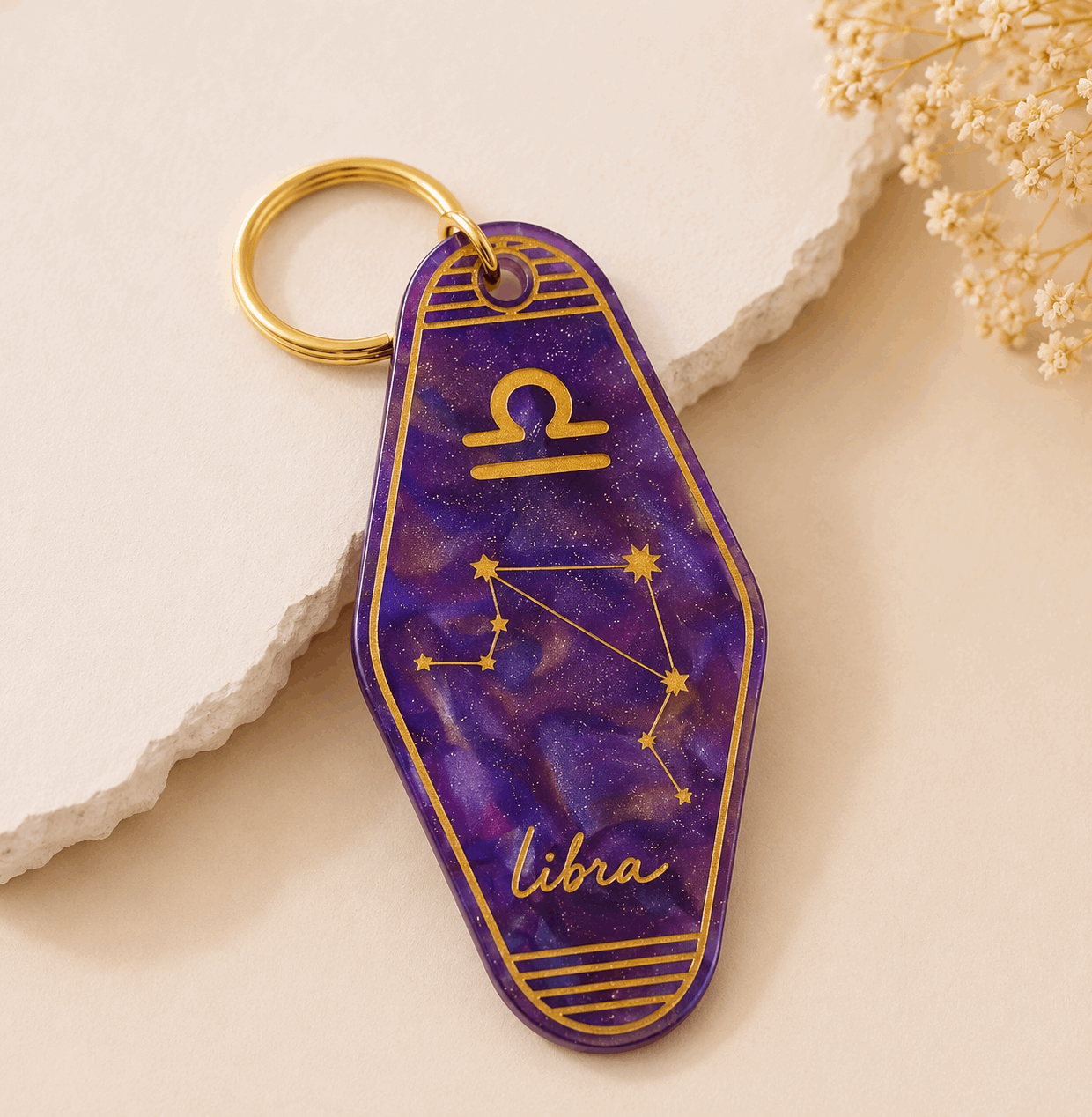 Purple keychain with Libra zodiac design on a light beige background